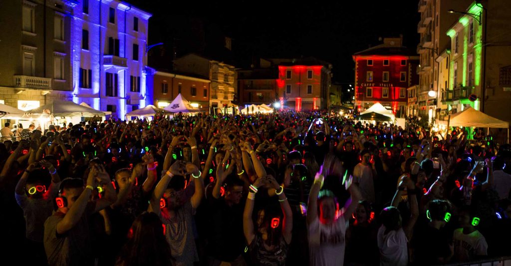 Town square at night full of people wearing silent disco headphones