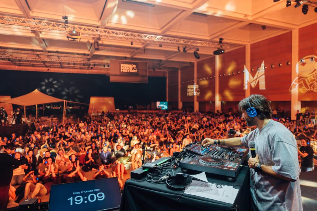 DJ wearing silent disco headphones in front of a large crowd on headphones
